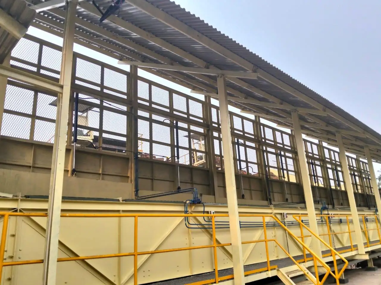 Loading ramp structure with hydraulic cylinders and piping along the hopper wall