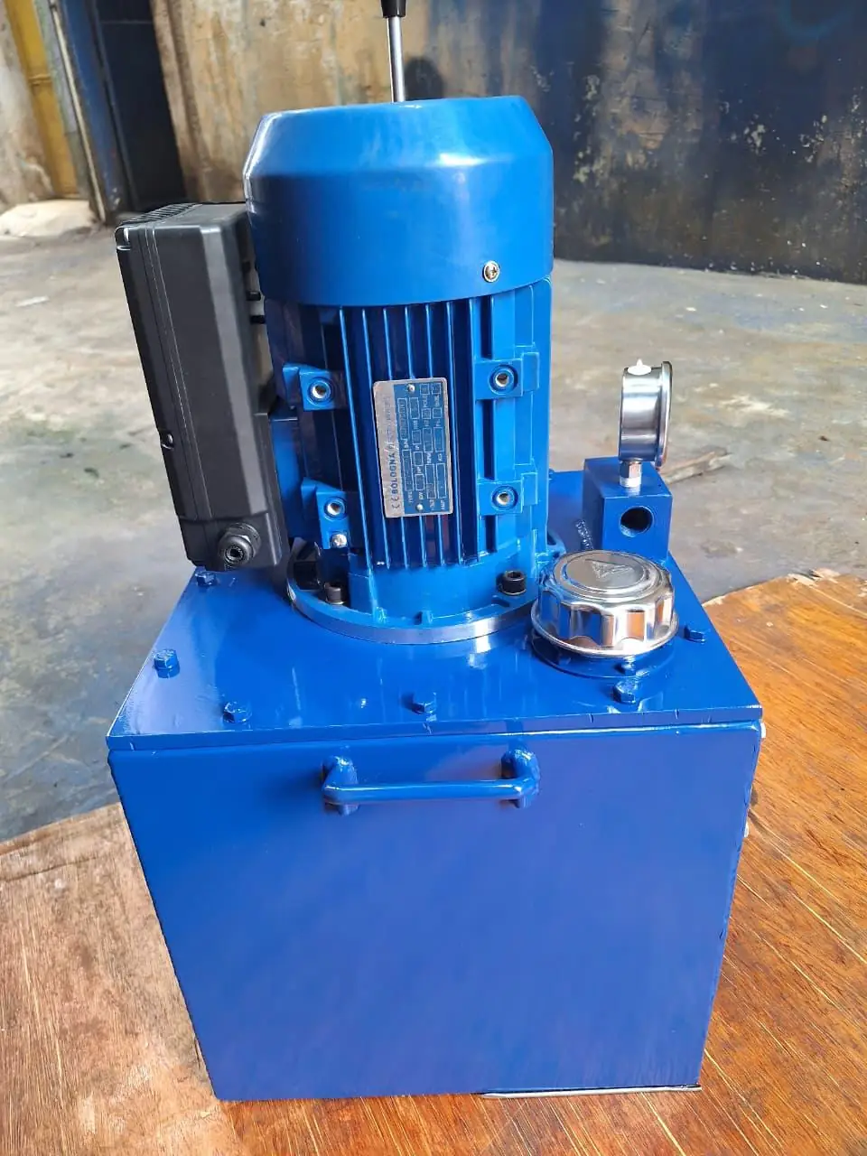 Mini hydraulic power pack with motor nameplate, filler cap and pressure gauge on a blue oil tank